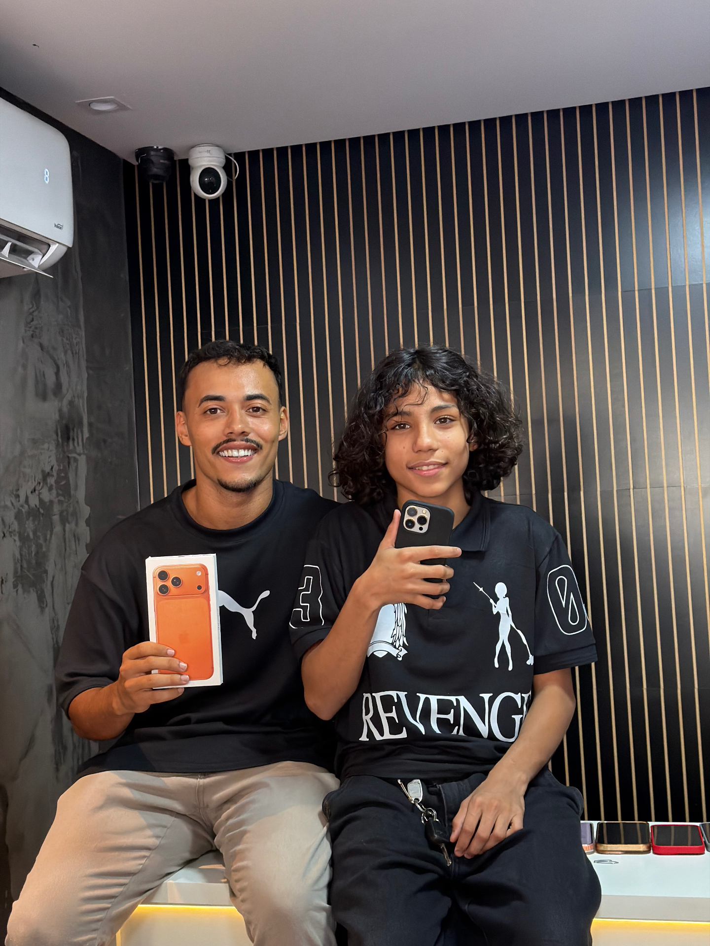 Equipe TECHCEL com cliente na loja segurando um iPhone 17 Pro Max
